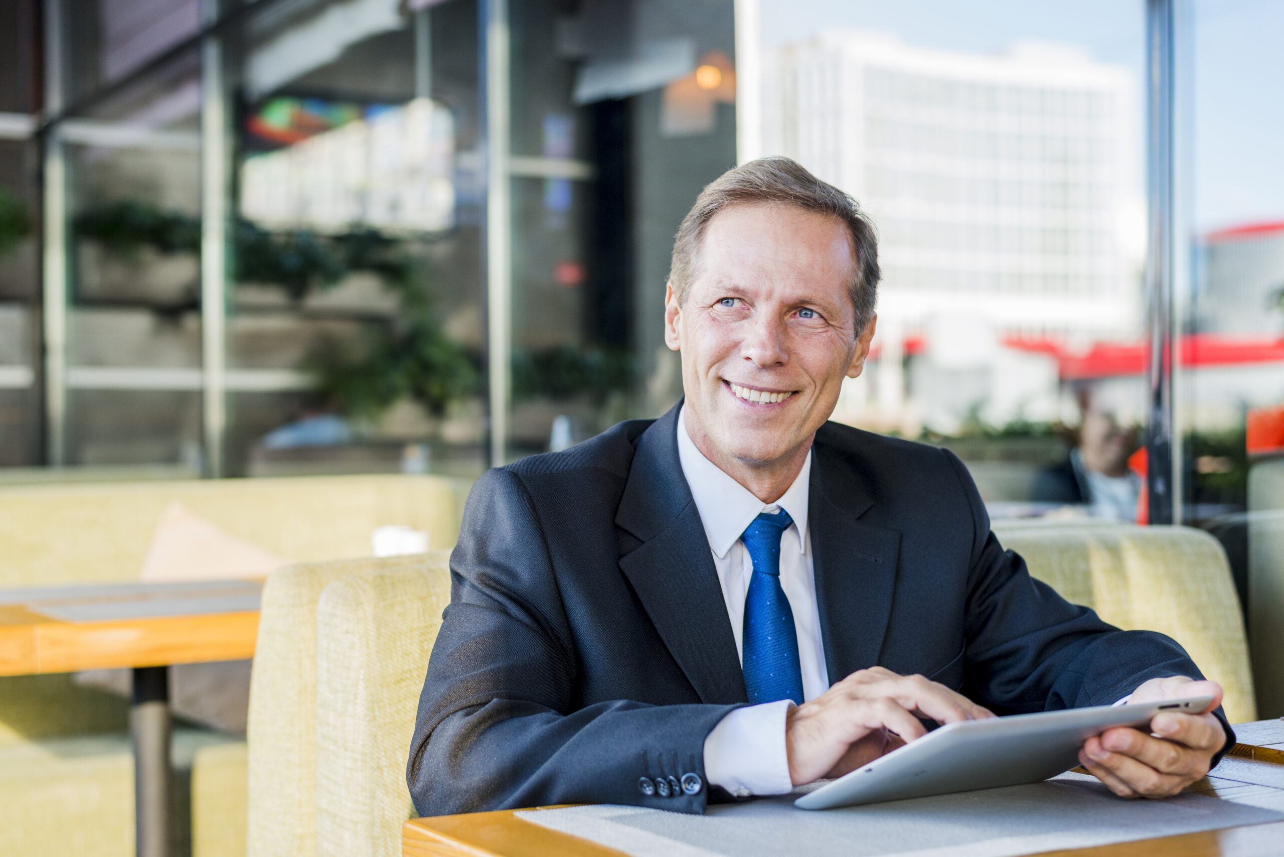 smiling mature businessman using digital tablet caf